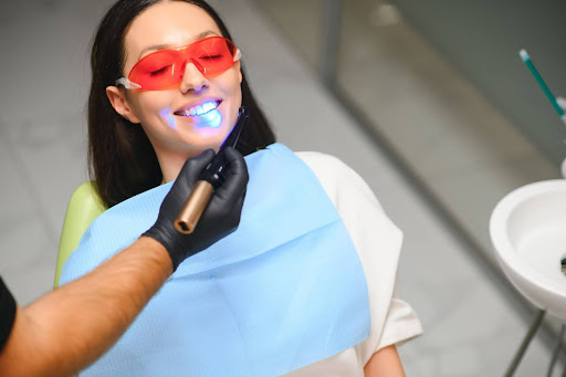 Female patient having a dental filling cured with blue light in a dentist's office.