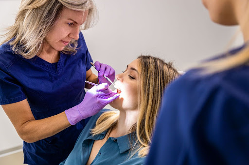 Female dentist with assistant performing an oral exam in a dental office.