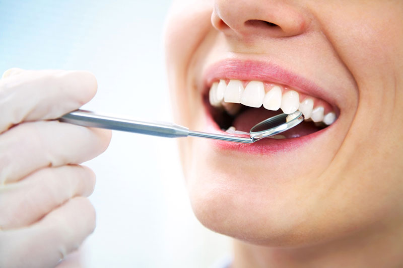 A dentist checking the teeth of a patient.